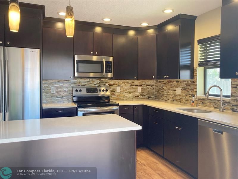 a kitchen with kitchen island granite countertop a sink stainless steel appliances and cabinets