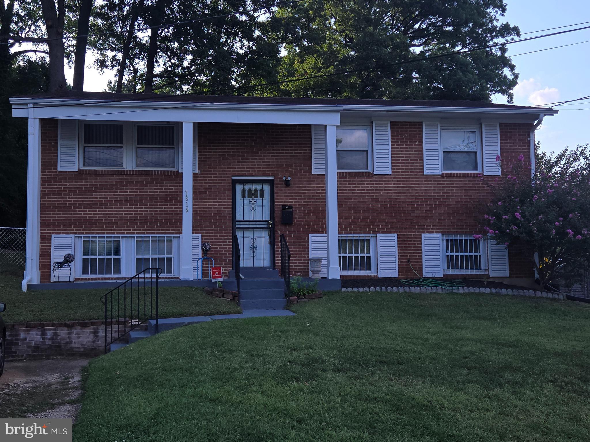 a brick house that has a small yard and large trees