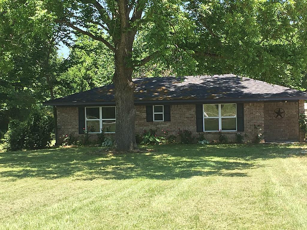 a front view of a house with a garden and trees