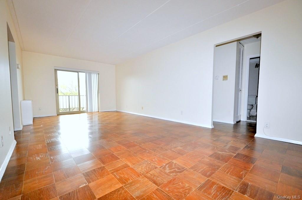 a view of an empty room with window and wooden floor