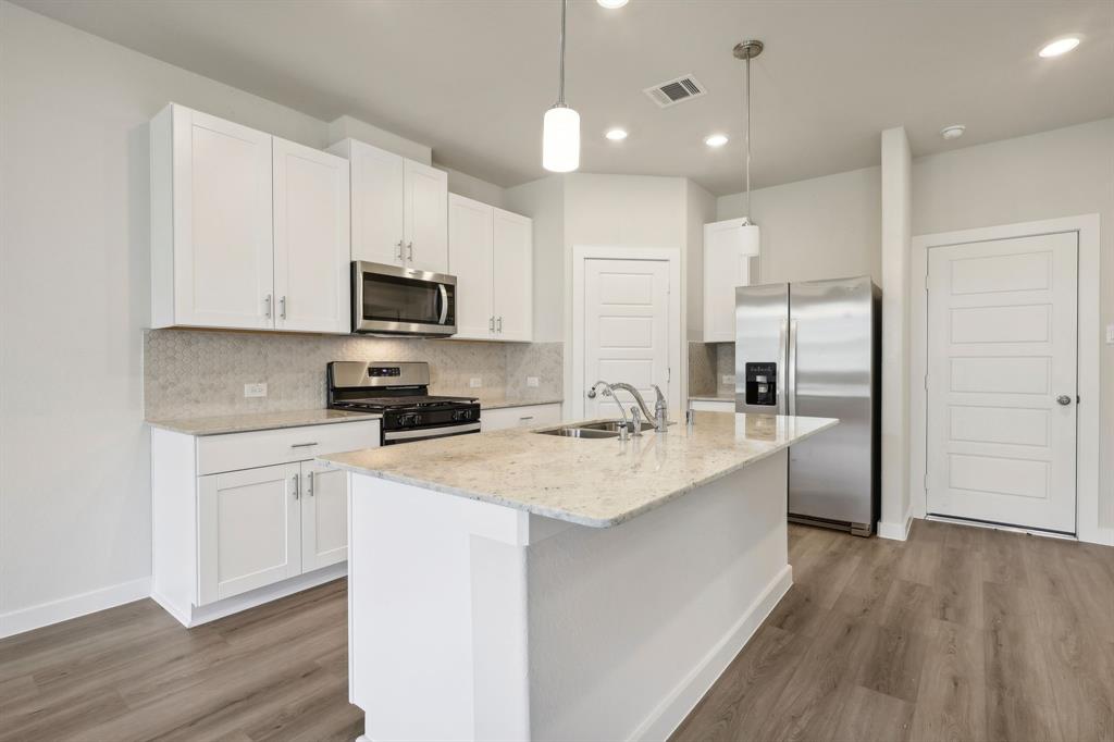 a kitchen with a refrigerator a sink and a stove top oven with wooden floor