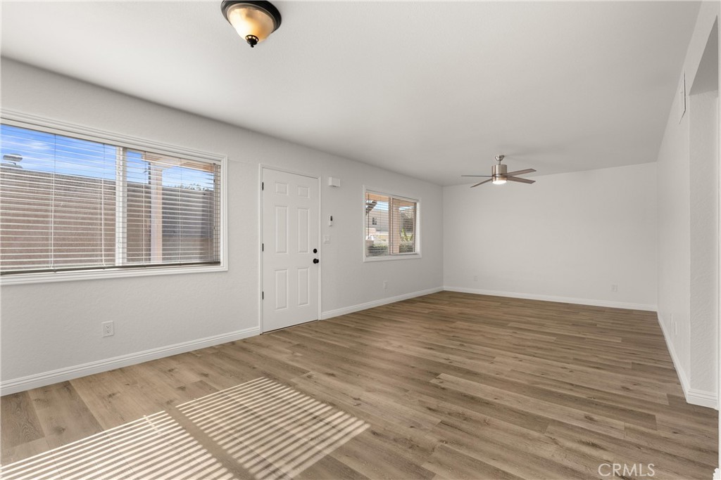 a view of an empty room with wooden floor and a window