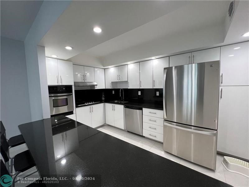 a view of a refrigerator in kitchen and stainless steel appliances wooden floor