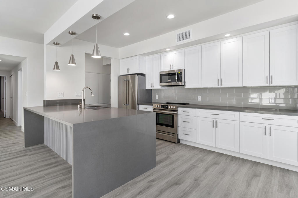 a kitchen with granite countertop white cabinets and stainless steel appliances