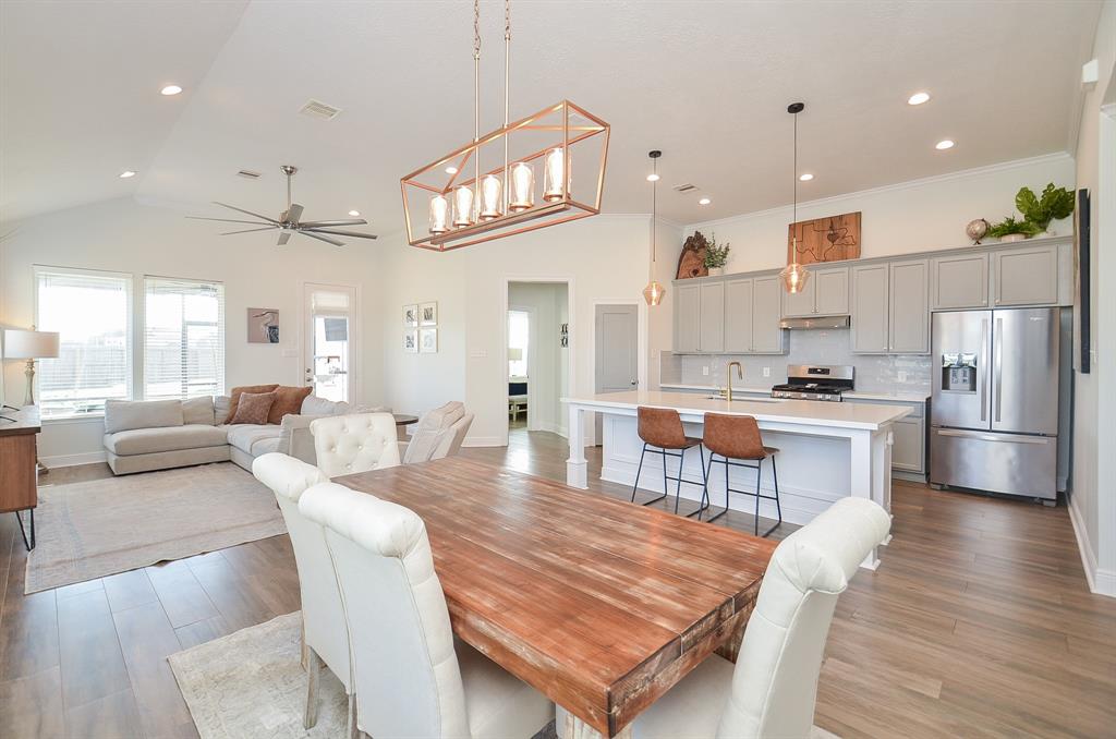 a living room with stainless steel appliances furniture a dining table and kitchen view