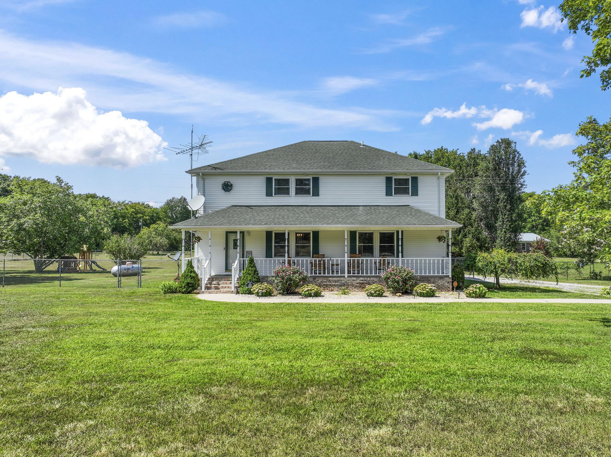 a front view of a house with garden and trees