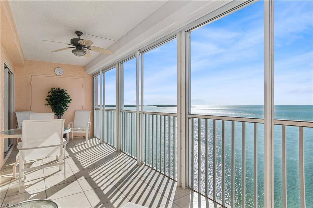 Sunroom with ceiling fan and a water view