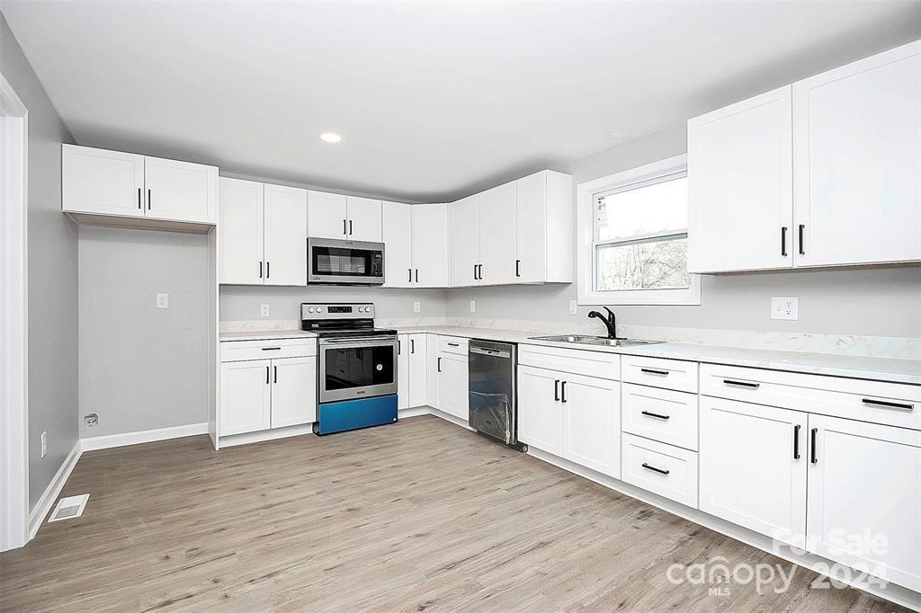 a kitchen with granite countertop white cabinets and stainless steel appliances