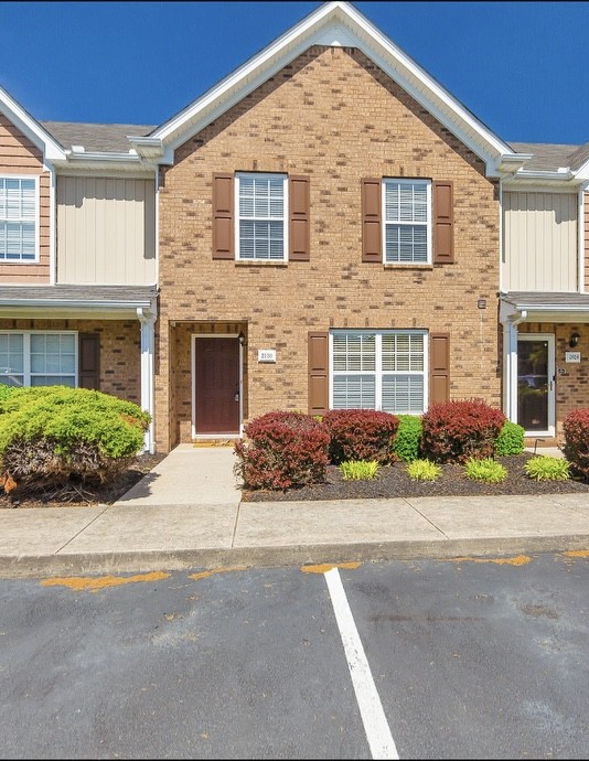 front view of a brick house with a small yard