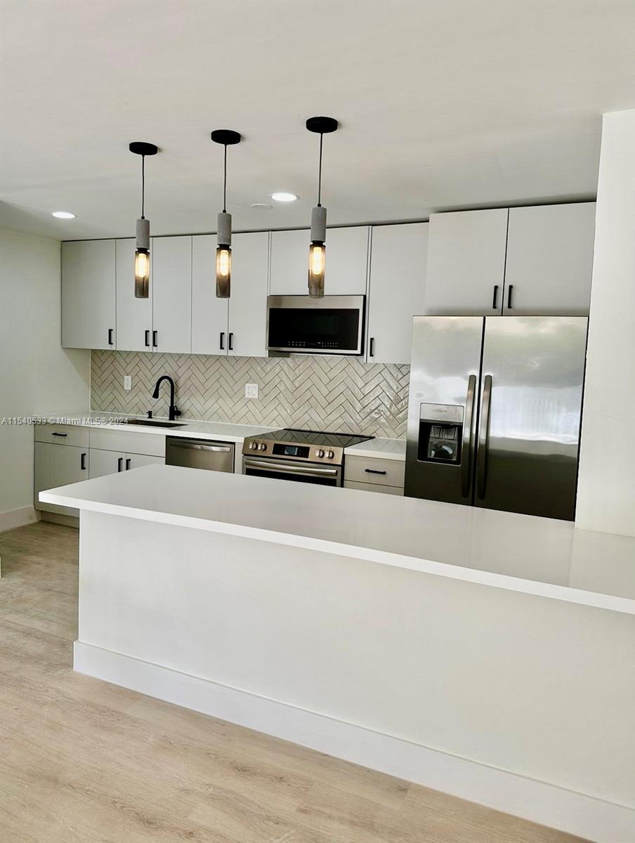 a kitchen with kitchen island stainless steel appliances a sink and a stove