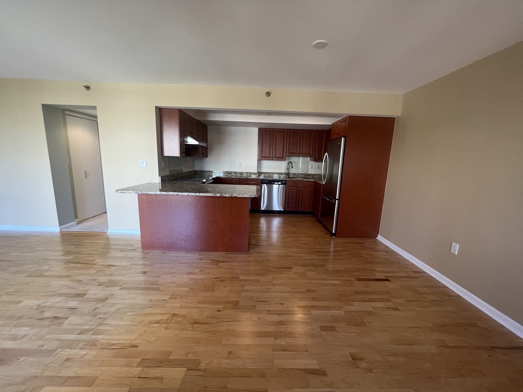 a view of kitchen with stainless steel appliances wooden floor and chair