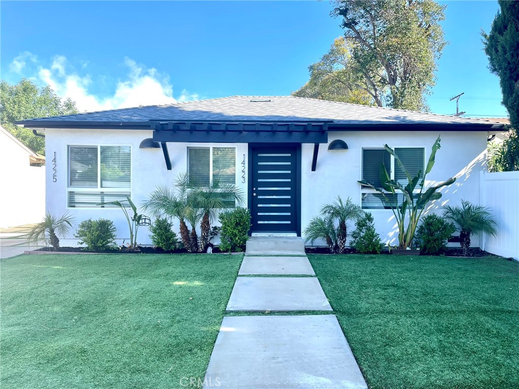 a front view of a house with a yard and potted plants