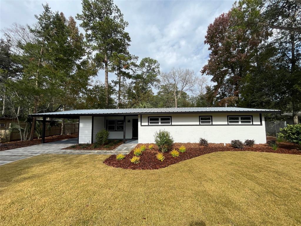 a front view of house with yard and trees in the background