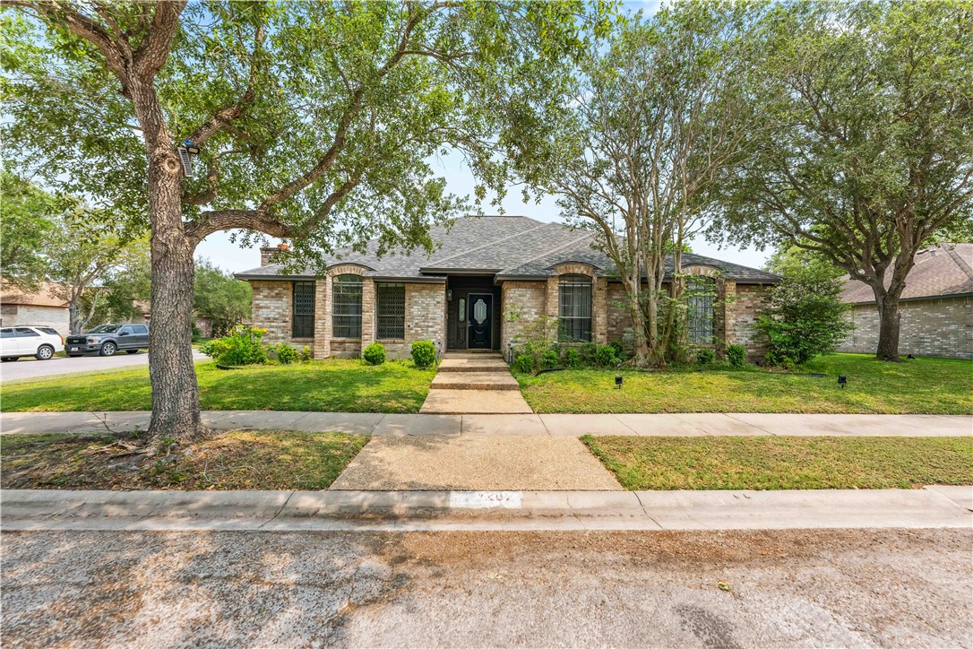 a front view of a house with a garden and trees