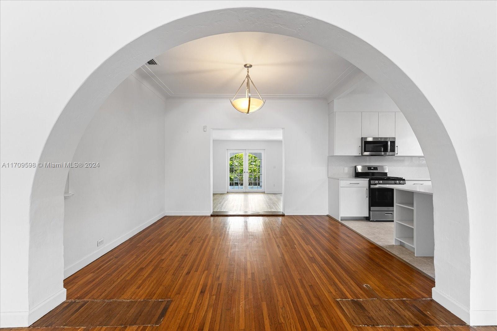 an empty room with wooden floor fireplace and windows