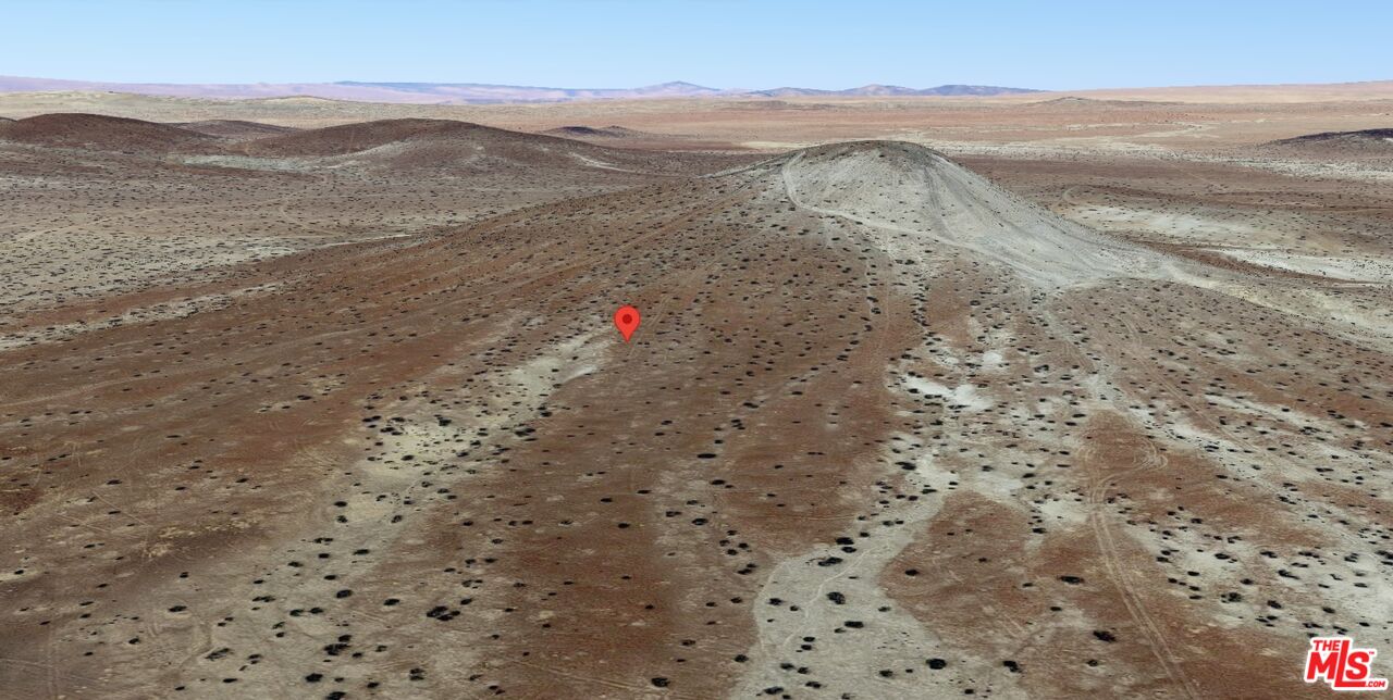 a view of a dry field with mountains in the background