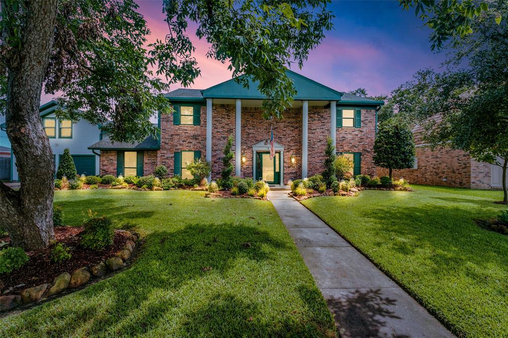 This home features a mix of brick and Hardie-Plank Siding. The house is showcased under a twilight sky creating a warm and inviting atmosphere.