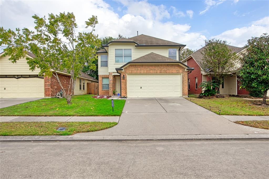 This is a two-story home with a brick and recently updated exterior paint. It is an attached two-car garage with a well-maintained front lawn and a tree.