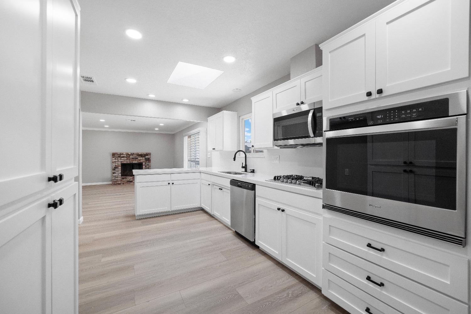 a kitchen with granite countertop white cabinets and stainless steel appliances