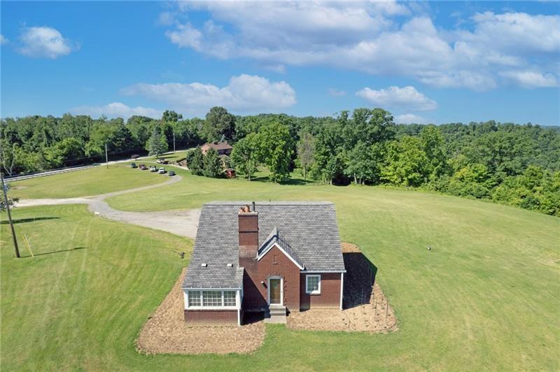 a view of a big house with a big yard and large trees