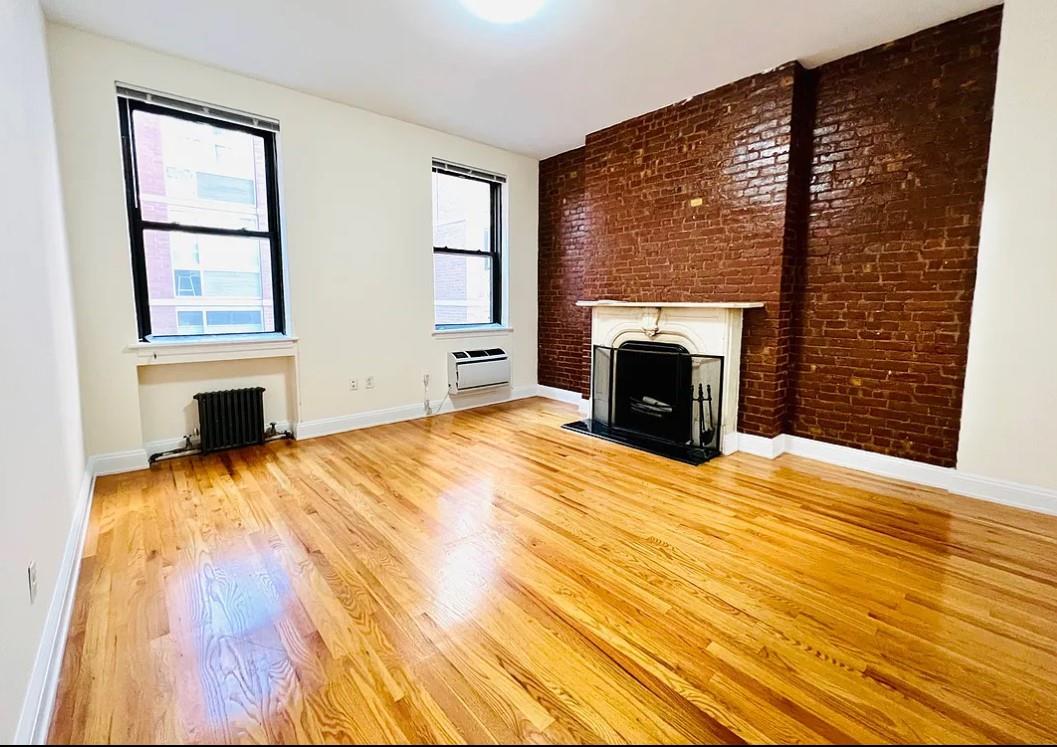 a view of empty room with fireplace and wooden floor