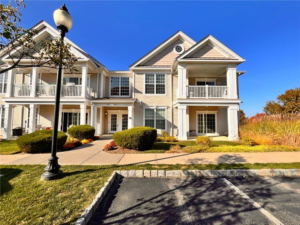 View of front of property with french doors, a balcony, and a front lawn