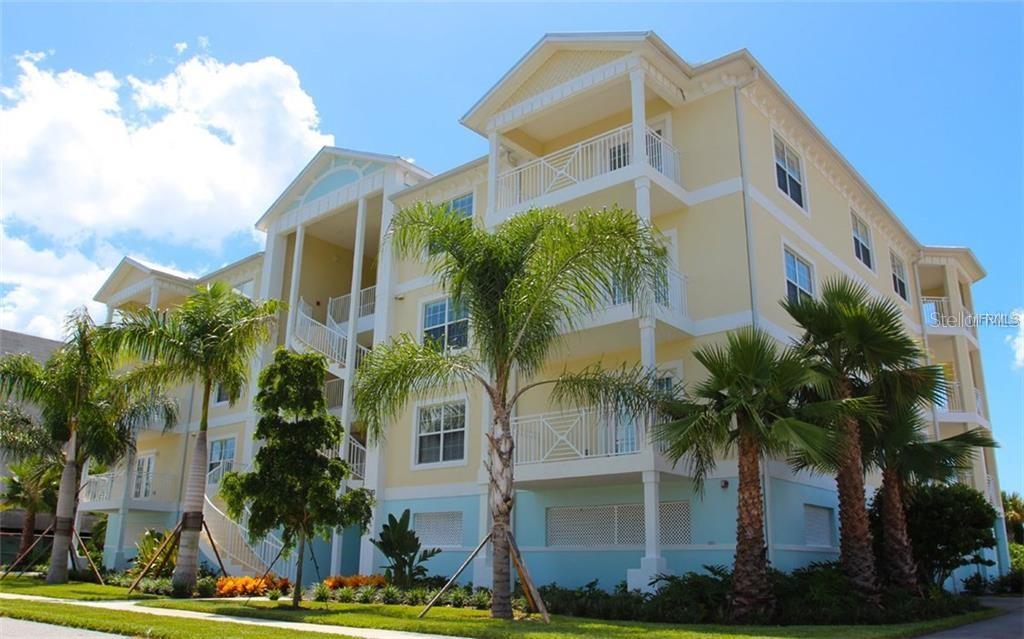 a front view of multi story residential apartment building with yard and parking