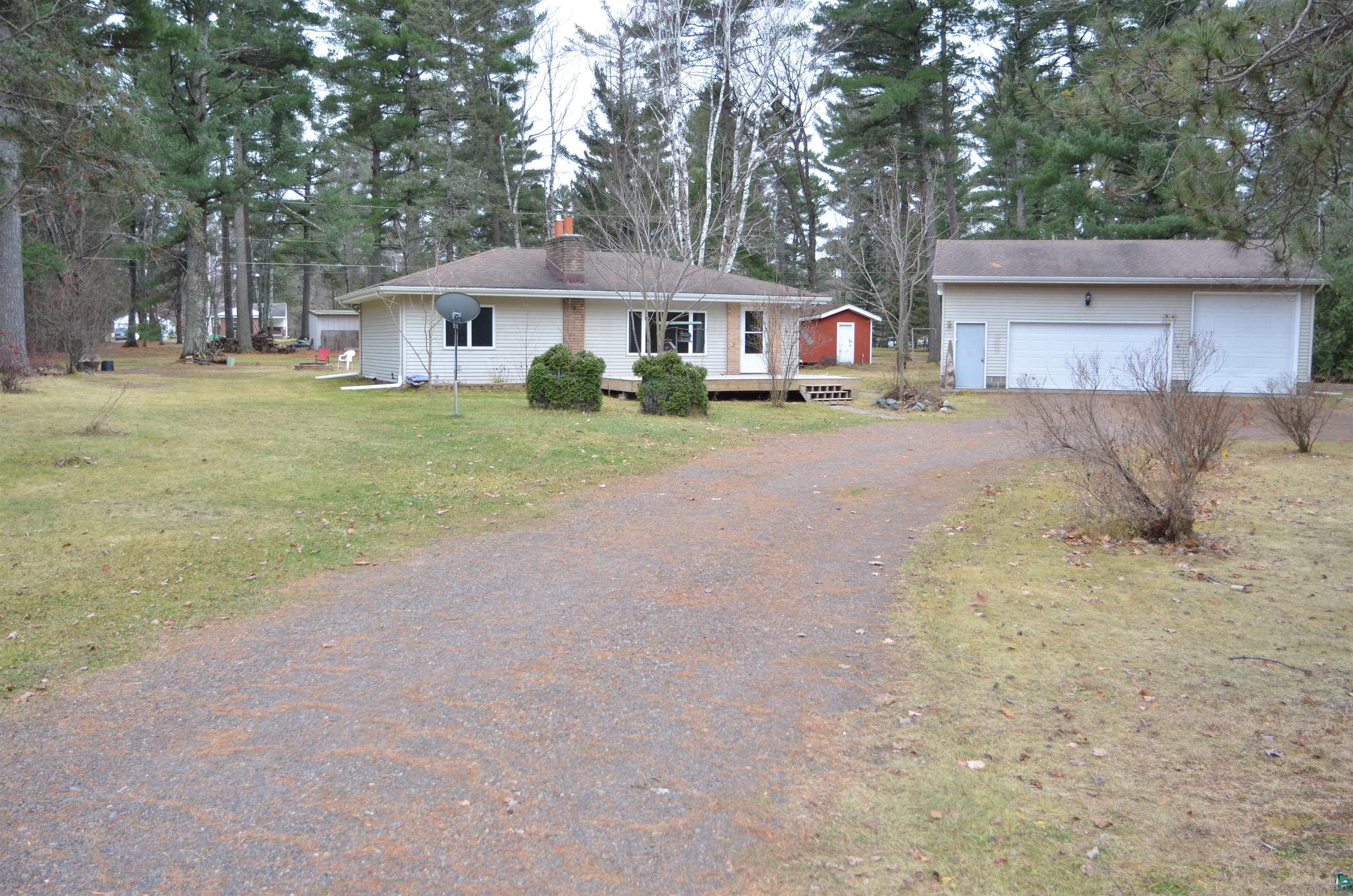 Ranch-style home with a garage, a deck, and a front lawn