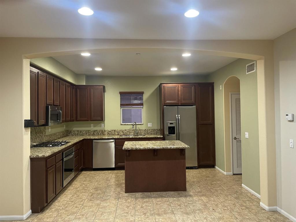 a large kitchen with stainless steel appliances kitchen island granite countertop a stove and a sink