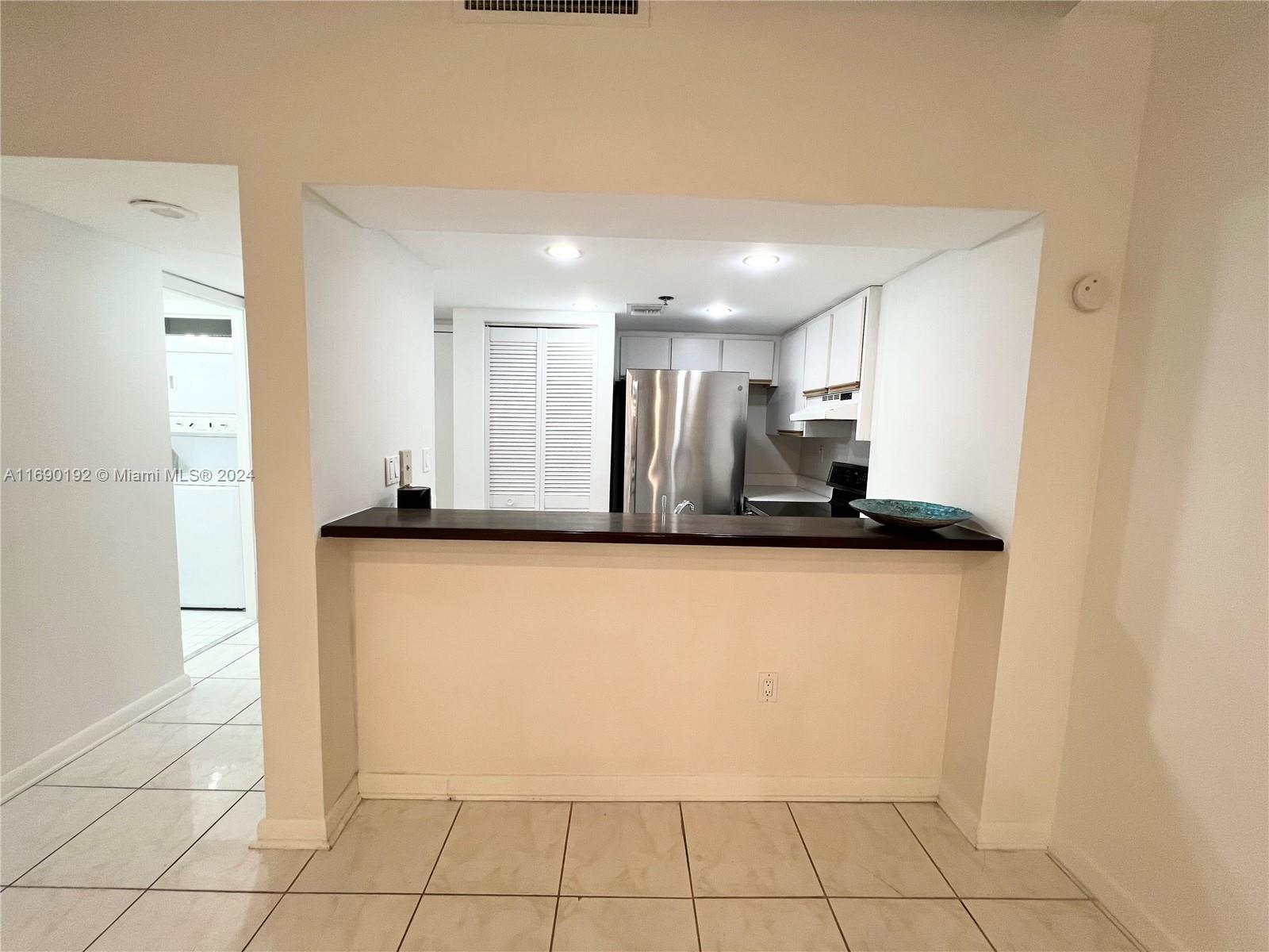 a view of a refrigerator in kitchen and an empty room