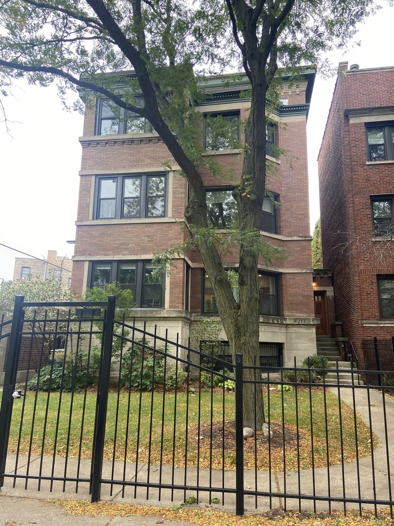 a view of a brick house with large windows and a table and chairs