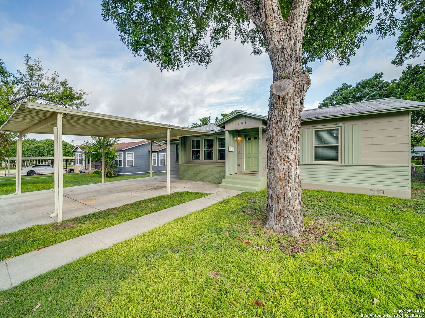 a view of a house with a yard and a large tree