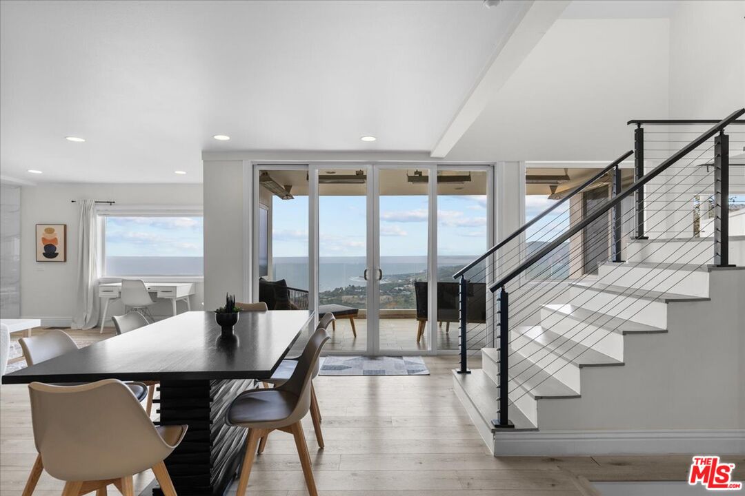 a dining room with furniture large windows and wooden floor