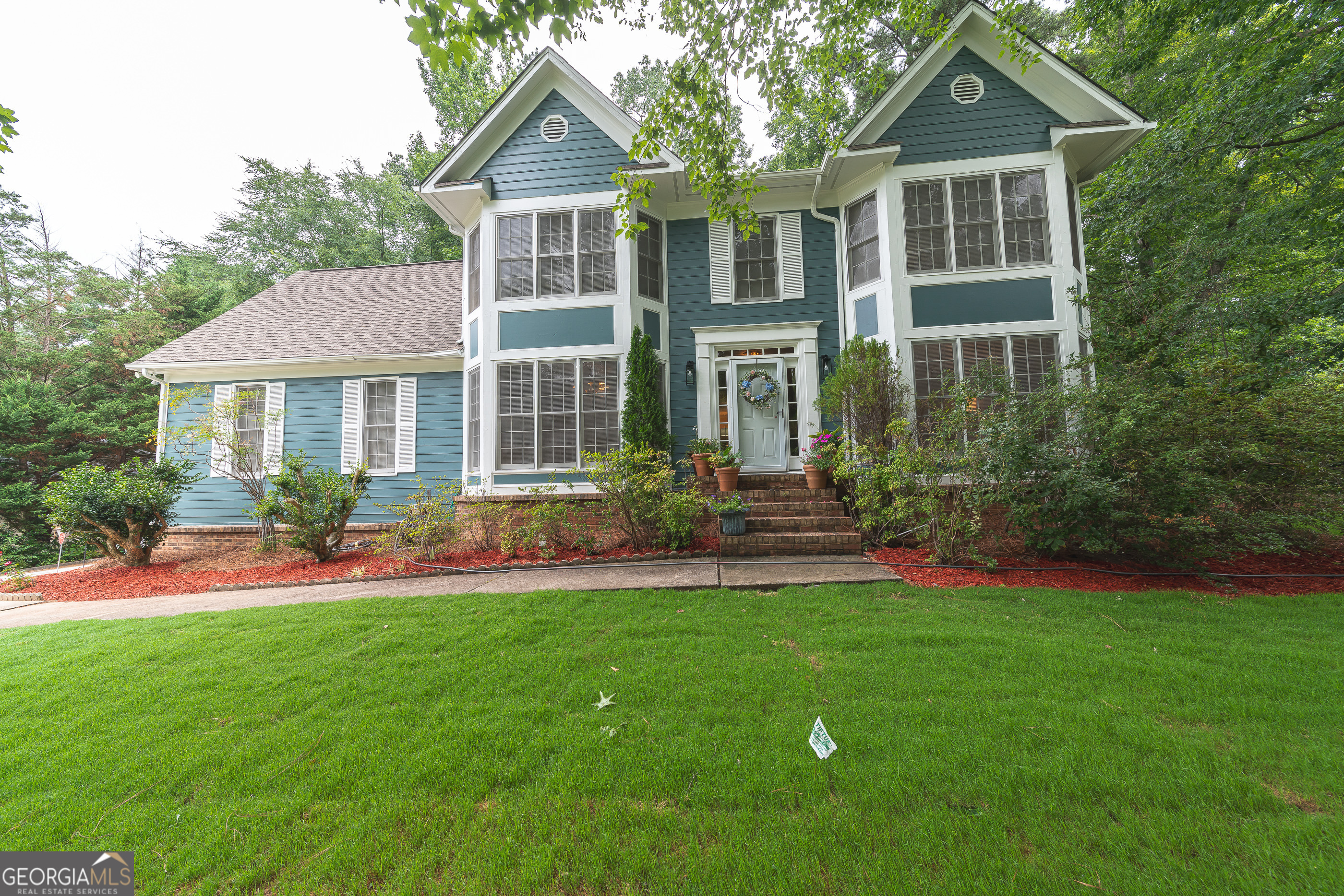 a front view of a house with a yard and green space