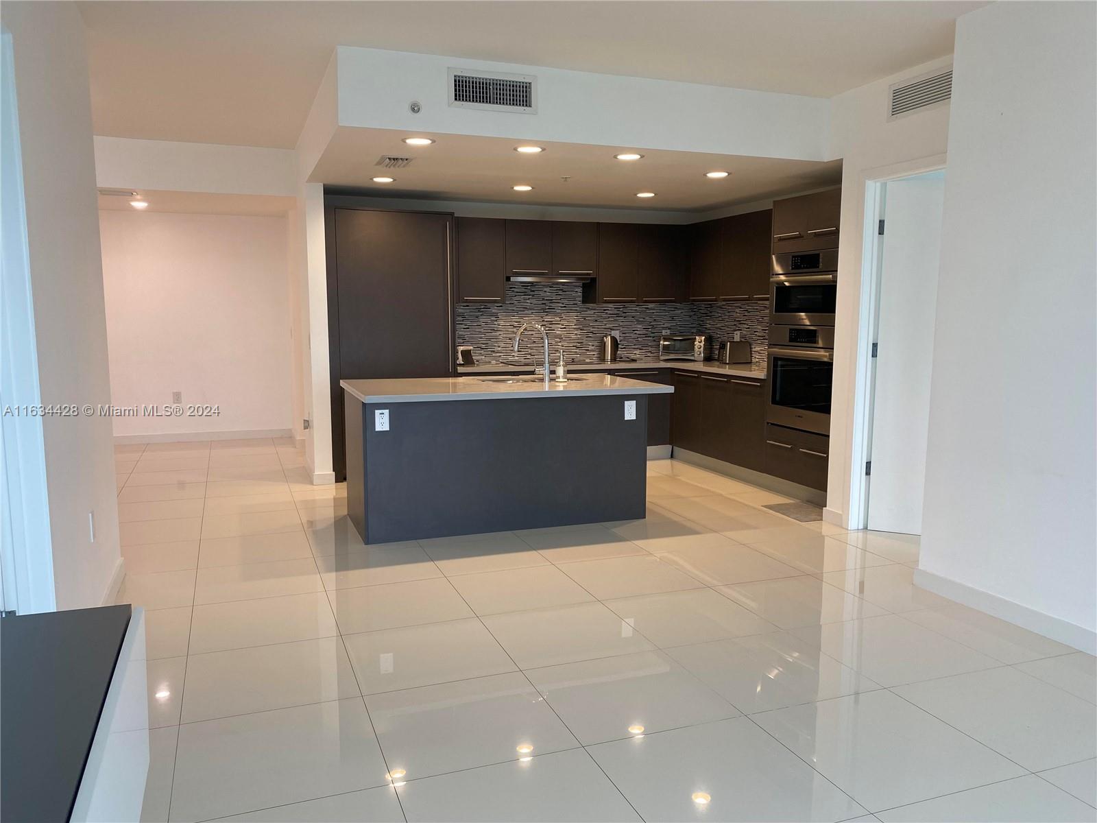 a large kitchen with stainless steel appliances a large counter top