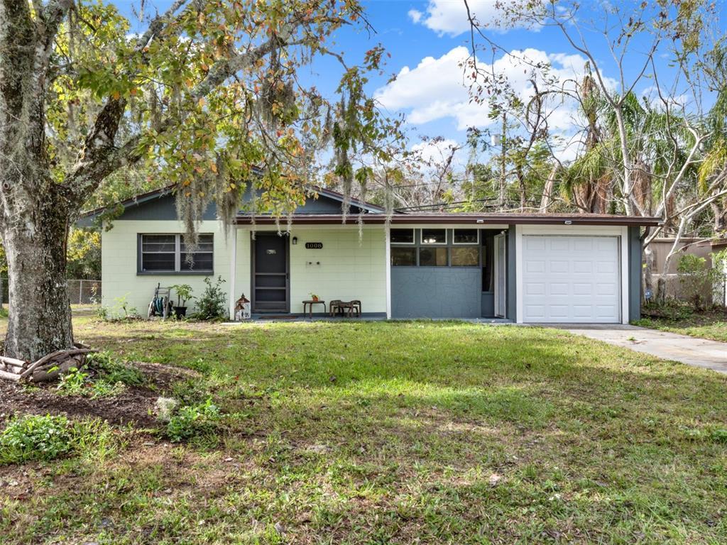 front view of house with a yard and trees