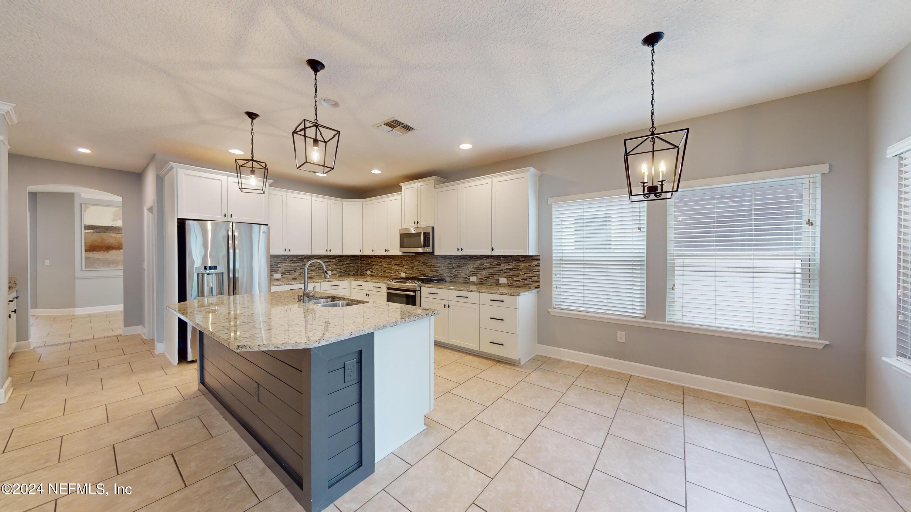 a large kitchen with kitchen island white cabinets and stainless steel appliances