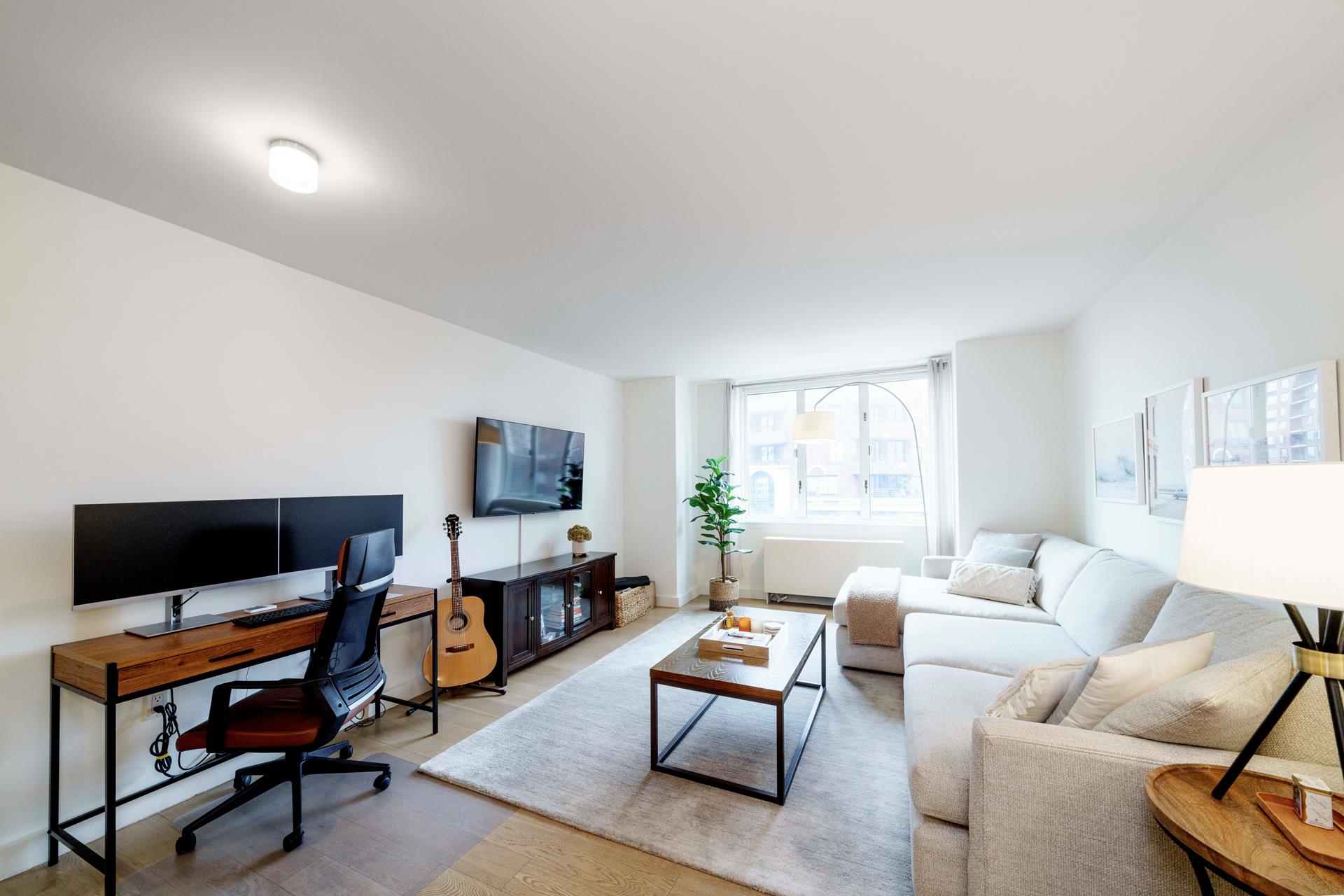 a living room with furniture a flat screen tv and a window