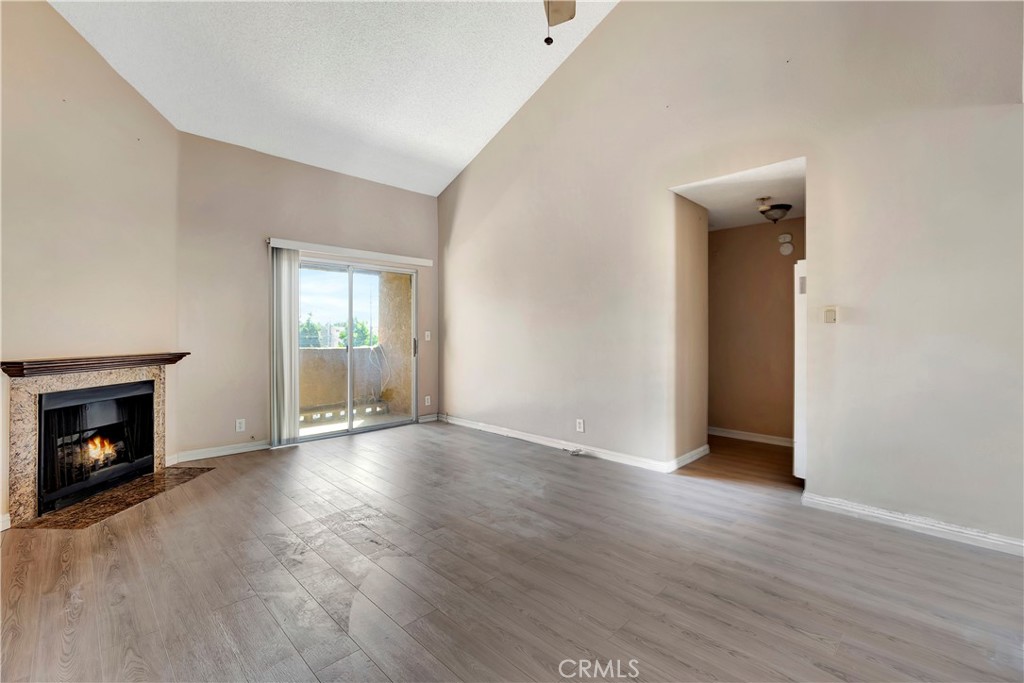 an empty room with wooden floor fireplace and windows