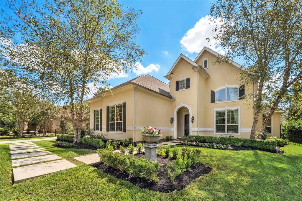 Featuring a well-manicured lawn, mature trees, and a welcoming pathway with gorgeous landscaping, leads to an arched entryway, this house welcomes you with prominent windows, a high-pitched roof, and a serene suburban setting.