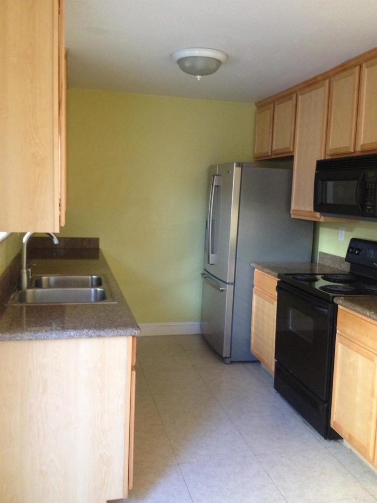 a kitchen with granite countertop a refrigerator and a stove top oven