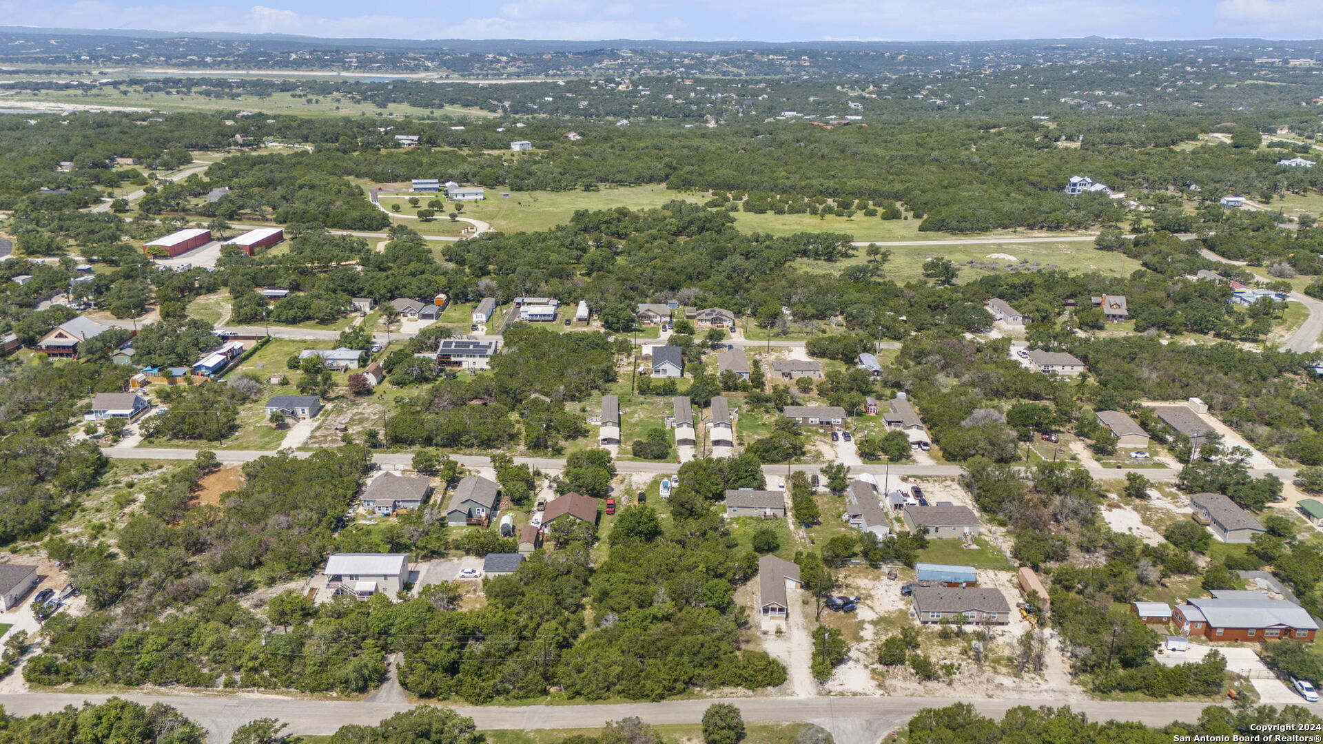 an aerial view of residential houses with outdoor space and trees