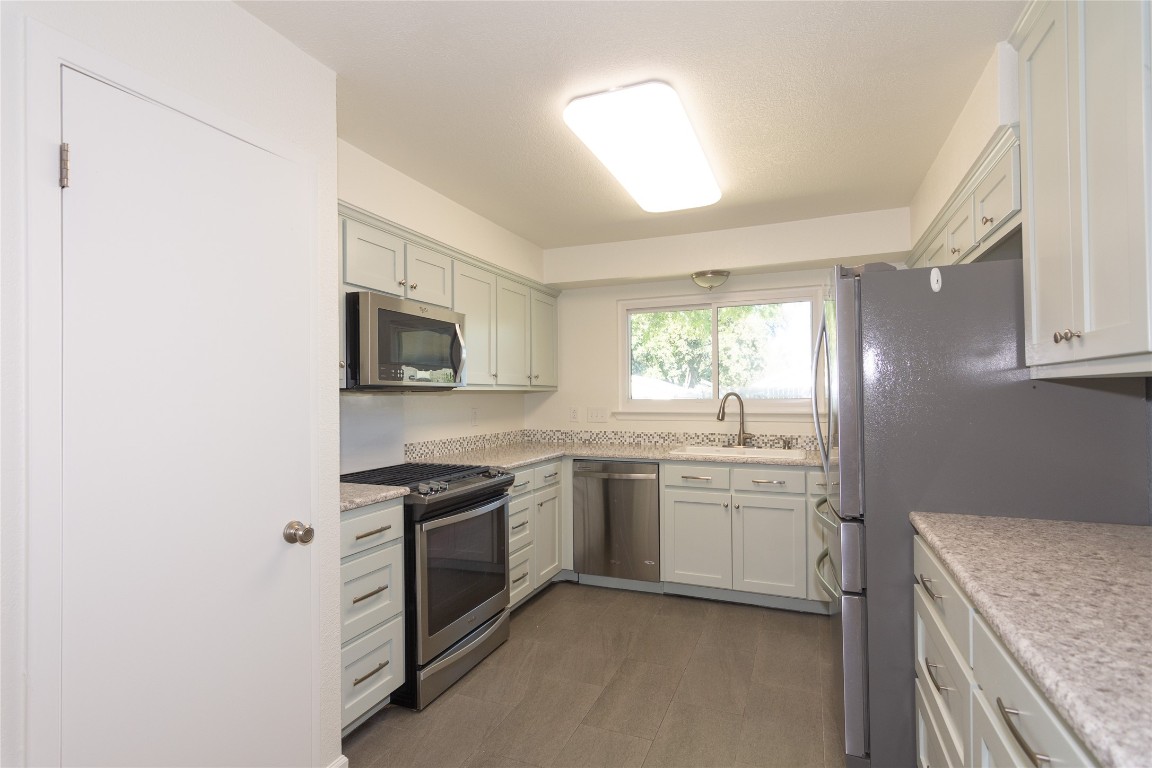 a kitchen with stainless steel appliances granite countertop a stove a sink and a microwave