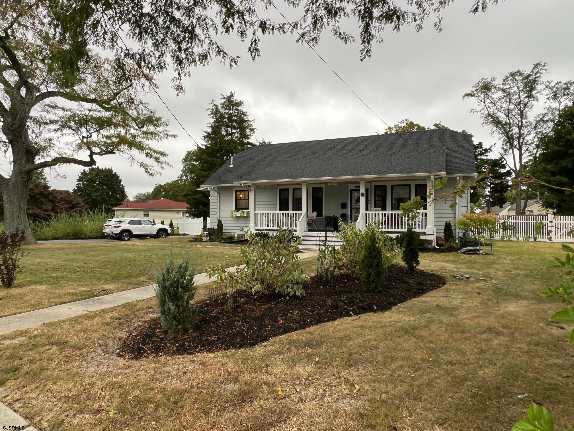 a front view of a house with a yard tree and outdoor seating