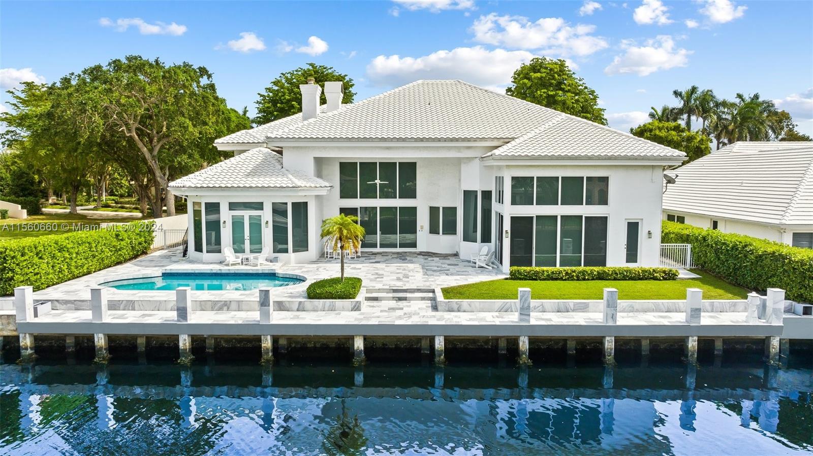 a view of a white house with a swimming pool and outdoor seating