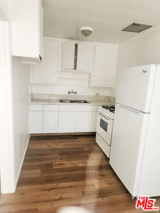 a kitchen with granite countertop white cabinets and white appliances