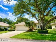 a front view of a house with a yard and tree