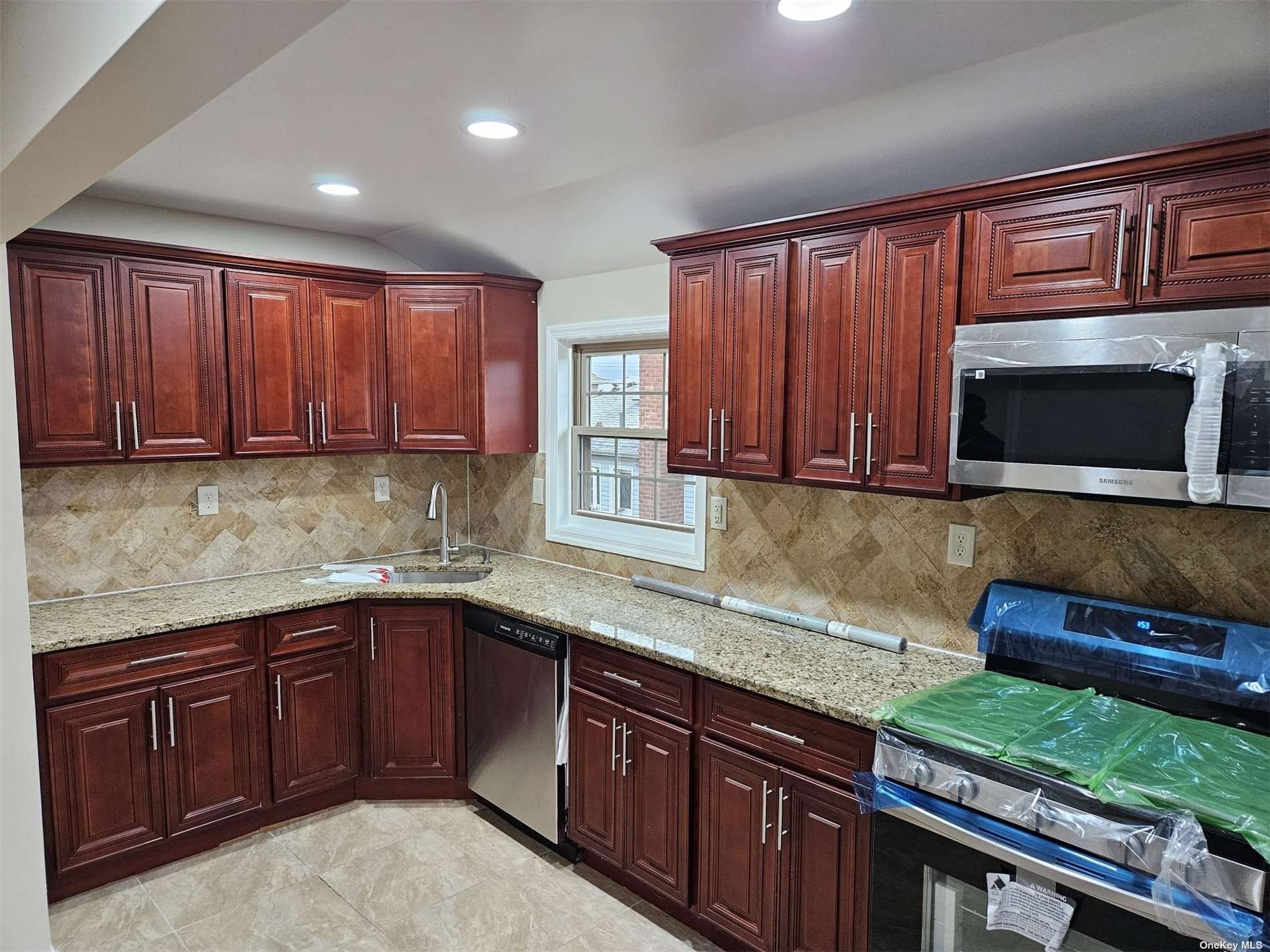 a kitchen with stainless steel appliances granite countertop wooden cabinets a stove top oven a sink and dishwasher