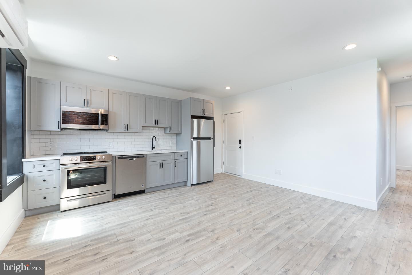 a large kitchen with stainless steel appliances granite countertop a stove a sink and white cabinets