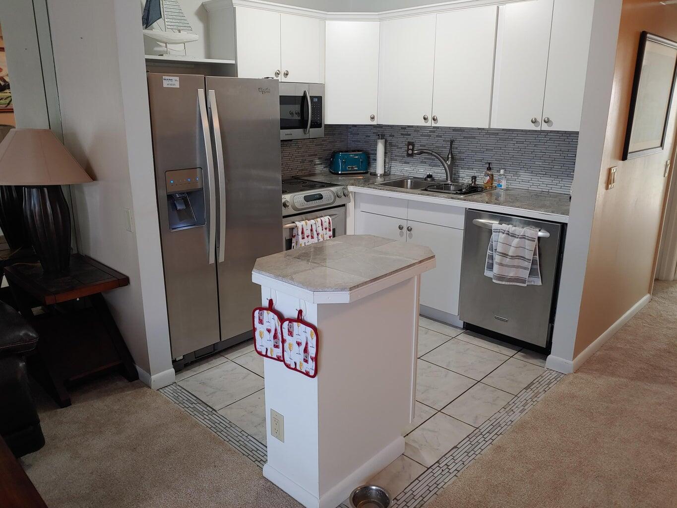 a kitchen with stainless steel appliances granite countertop a refrigerator a sink and a stove